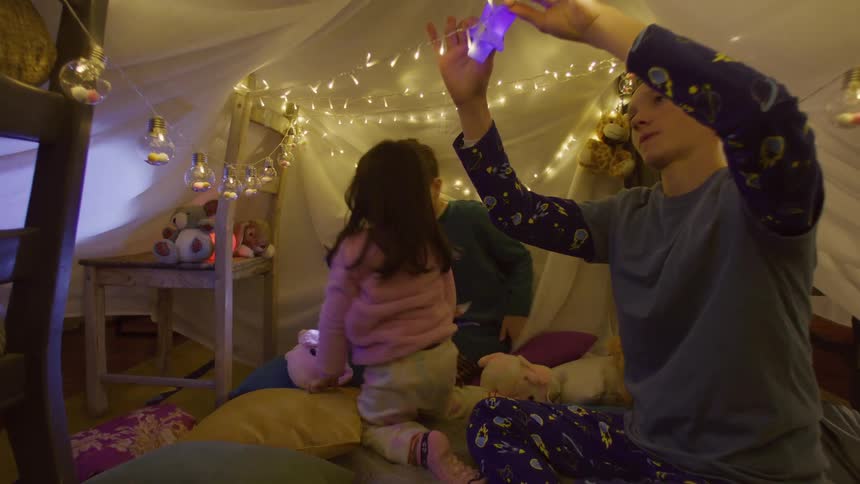 Children are putting lights inside the blanket tent