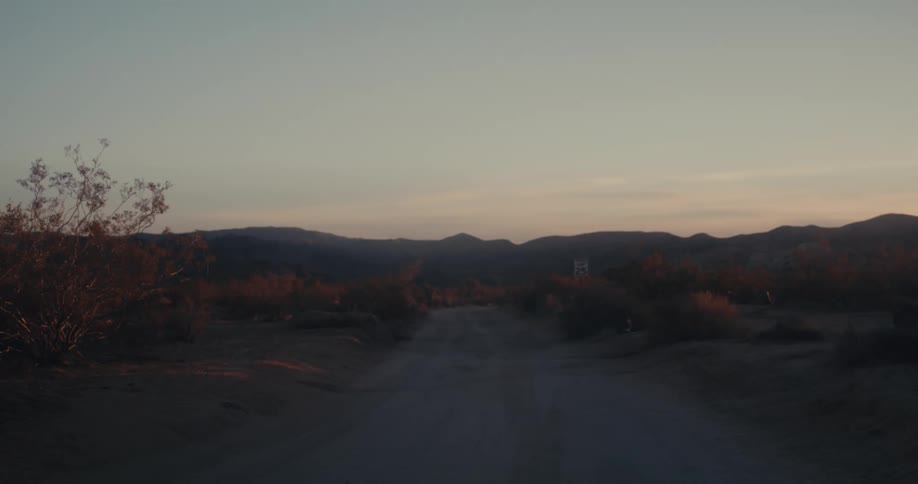 Landscape of a setting with desert vegetation and silhouettes of mountains on the horizon