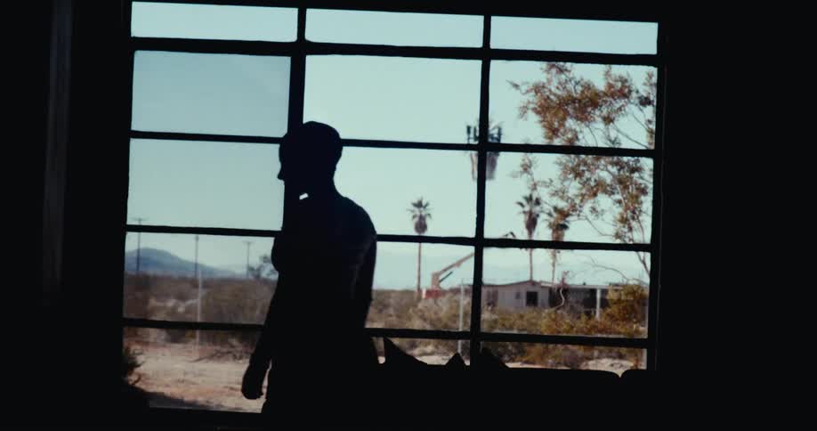 The silhouette of a person who is opening a dark door and he is walking forward in a dark environment