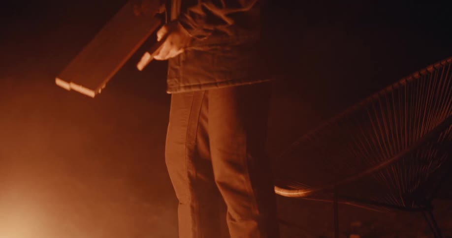 People throwing pieces of firewood into a bonfire at night