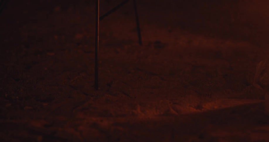 Bench on the sand with reflection of shadows and red lights