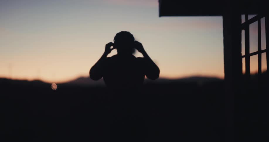 The silhouette of a muscular person walking forward in an environment that is completely dark with a clear sky