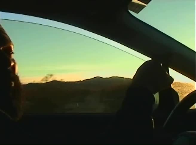 Man driving a car and pointing forward