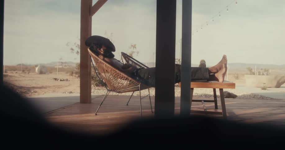 Person sleeping sitting on a chair with legs stretched out on a table in the backyard