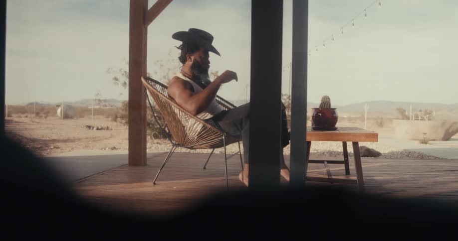 Man relaxing on the porch of a home near the desert gets up and walks into the house