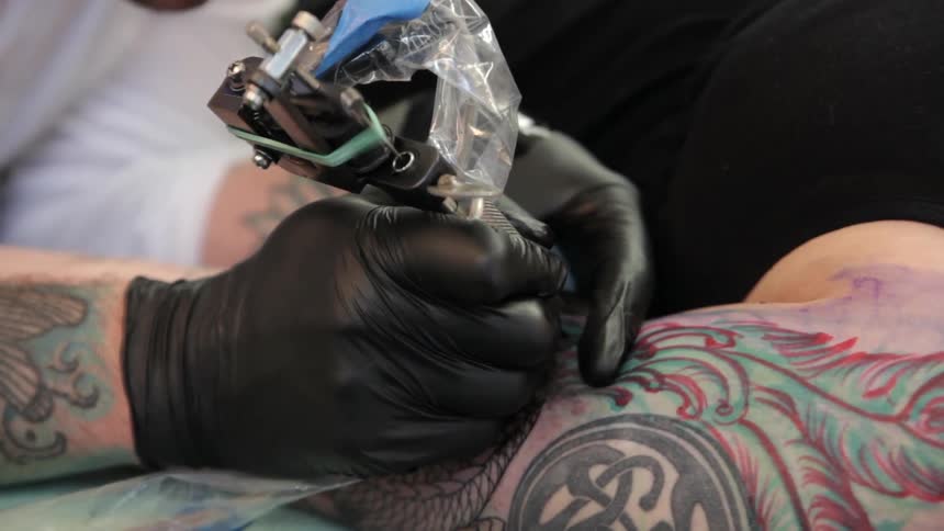 A tattoo artist works on a customer
