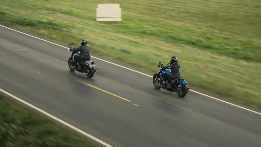 Two people riding a motorcycle through a natural area
