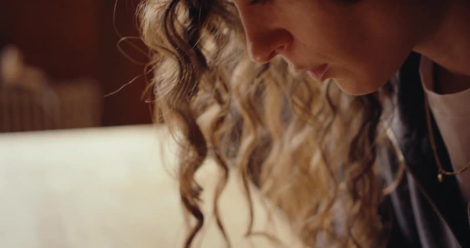A woman with curly hair scrolls through photos on her smartphone displaying an interior design image