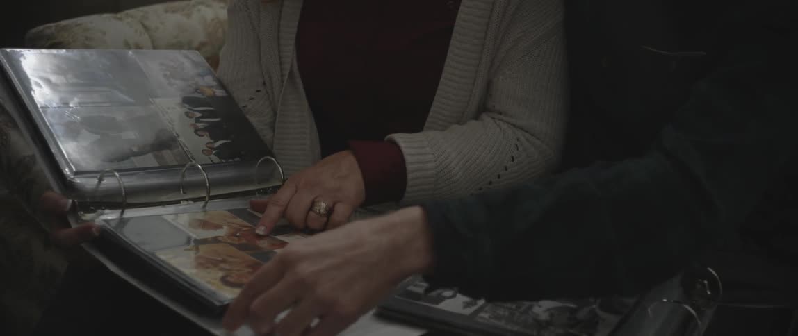 A man and woman look at photo albums while sitting on a couch