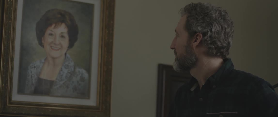 A man looks at a painting hanging on a wall