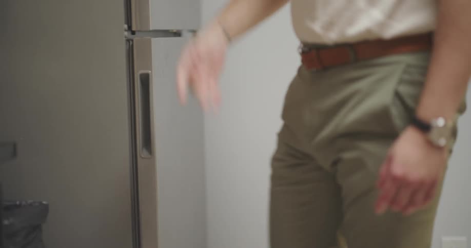 Man in a kitchen opening and closing a refrigerator door then opening a box on top of the sink