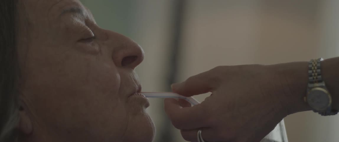 A woman gives an elderly woman a sip of water