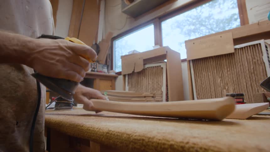 Carpenter with a machine sanding a piece of wood
