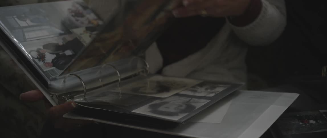 A man and woman sit on a couch browsing photo albums