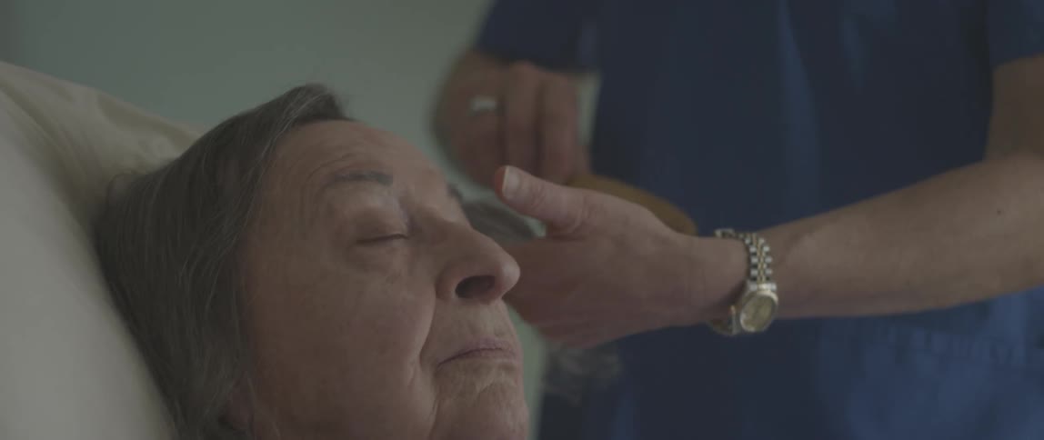 A nurse brushes the hair of an older patient