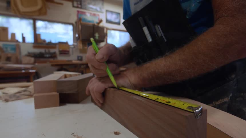 Carpenter using a pencil and tape measure on a piece of wood