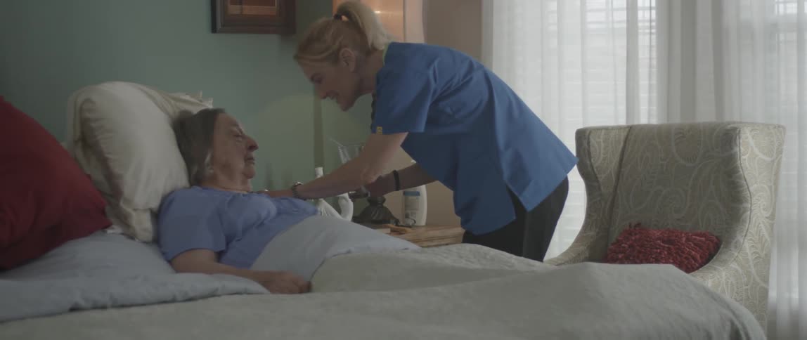 A nurse gives an elderly woman a sip of water