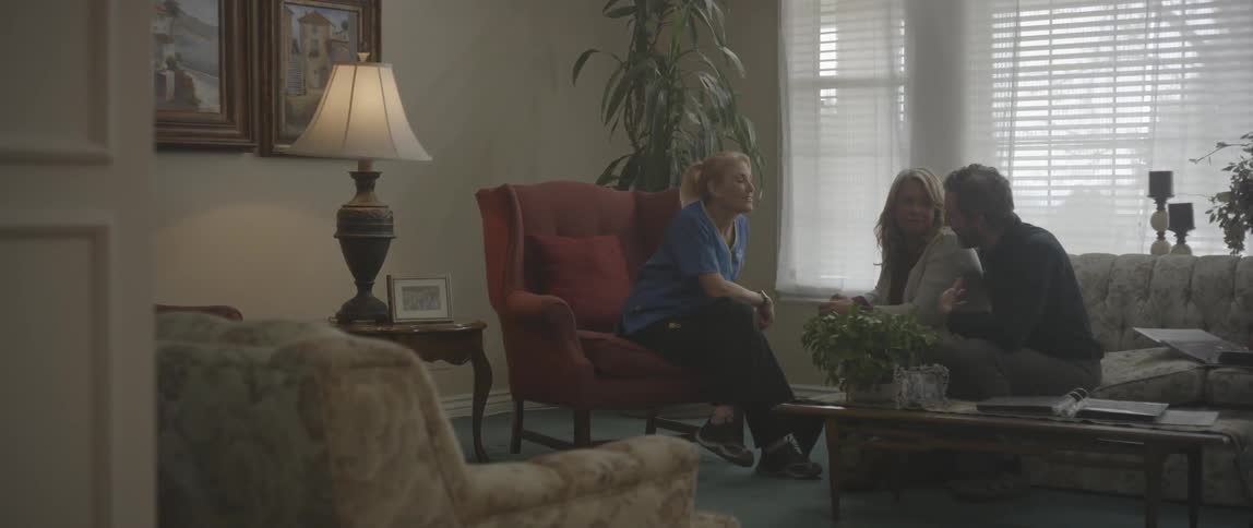 A man and woman sit and converse with a nurse
