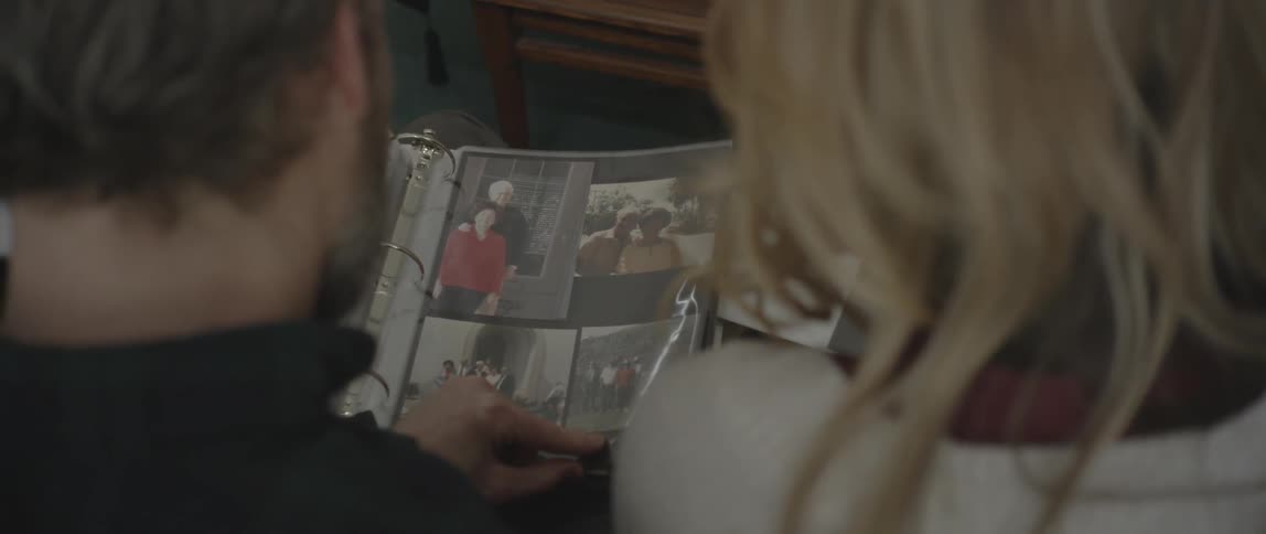 A man and woman sit on a couch browsing photo albums