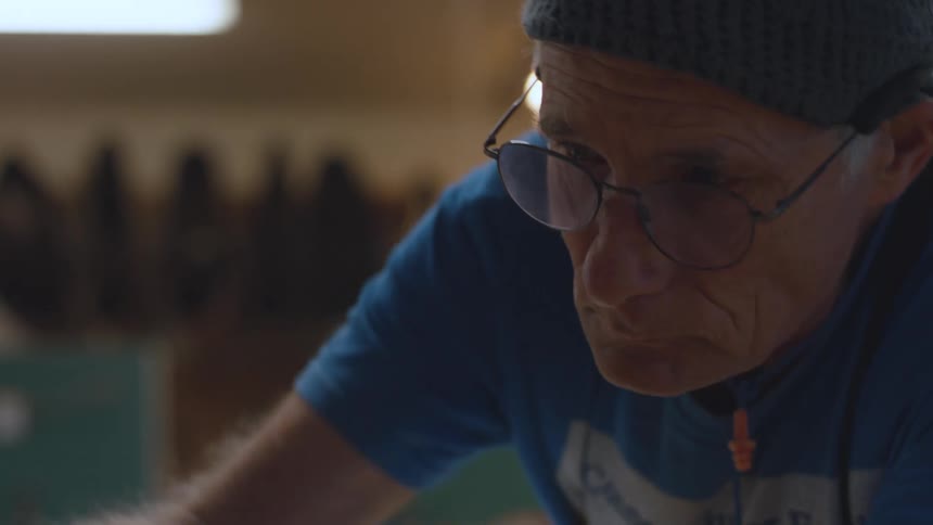 A carpenter in a workshop brushes the surface of a table