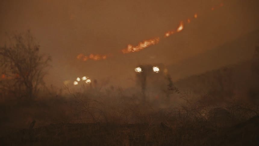 Cars drive up the hill as the forest burns