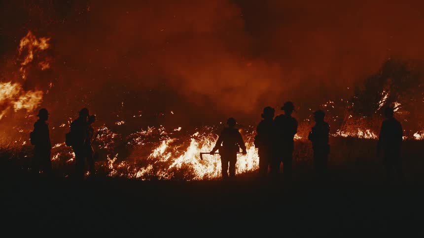 Silhouette of firefighters at a forest fire at night