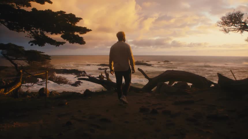 A man is walking towards the beach at sunrise
