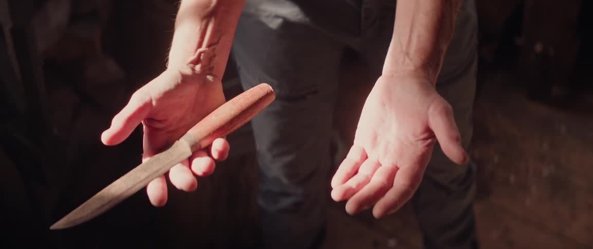 A person is holding a knife in their workshop