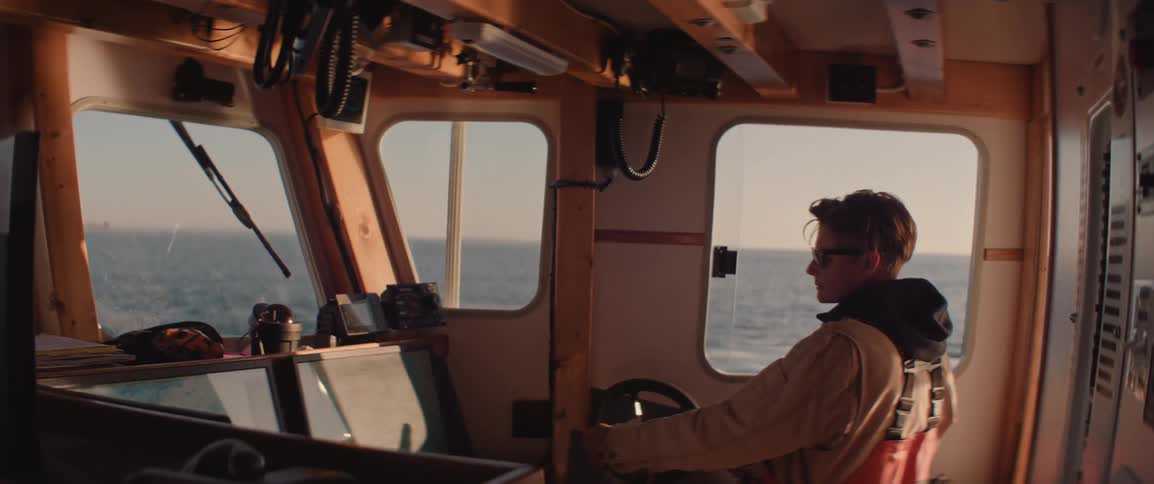 A woman is steering a boat in the ocean