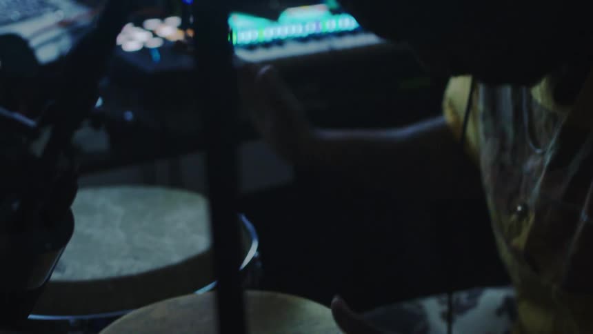 Man plays bongos in a dimly lit room