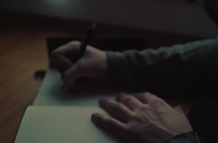 A man is writing with a pen in his notebook