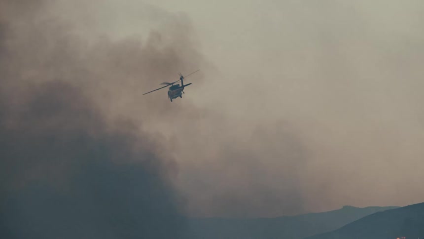 A helicopter dumps water on a wildfire