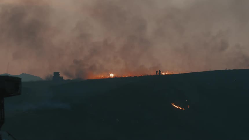 Tractor passing through a forest on fire in the mountains