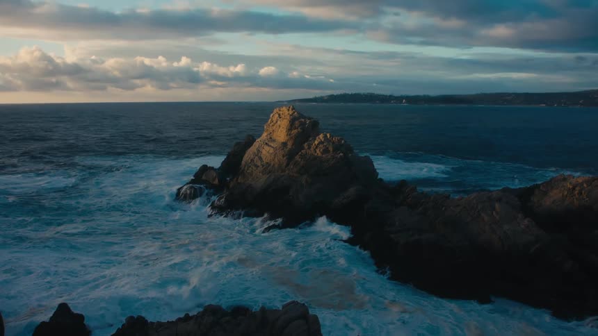 Rough waters crash against the rocks on the shore
