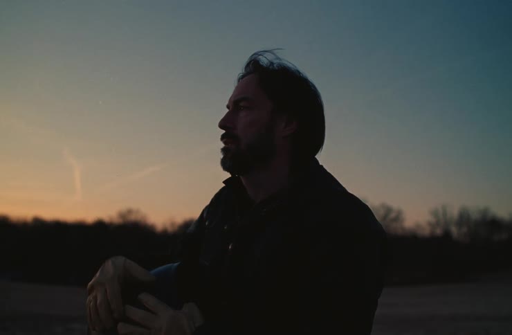 A man removes his helmet at sunset