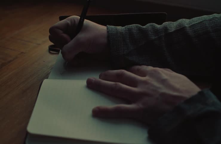 Hand opening a notebook and taking notes