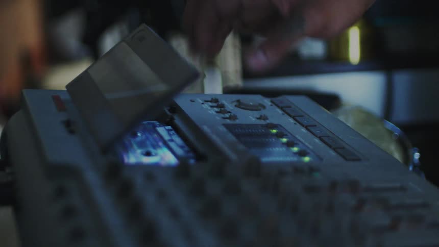 Hand adjusting a tape on a portable audio mixer