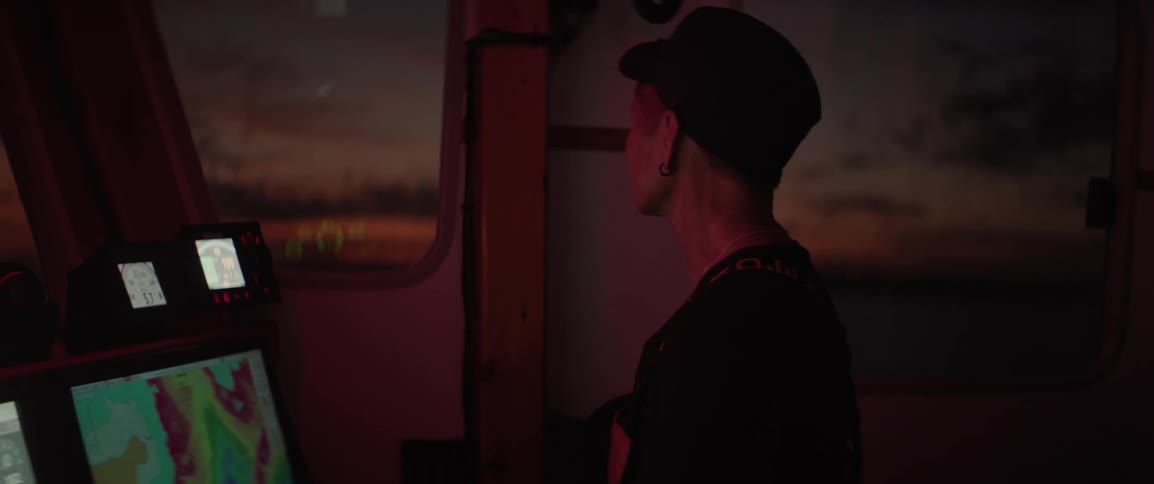Female sailor steering the boat from the cabin at dawn