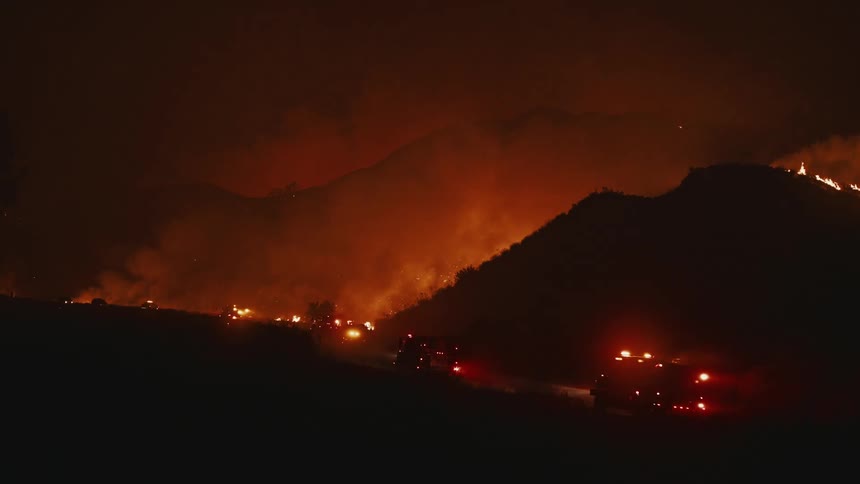 Emergency vehicles travel in the dark towards a forest fire