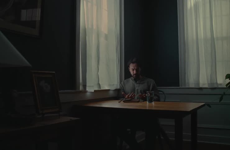 A man is examining his hands at the table