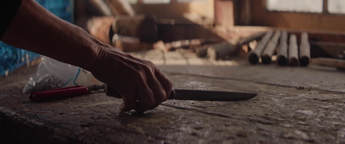 Hand picking up a knife on top of a wooden table