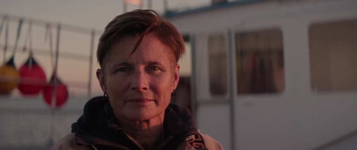The face of a woman with short hair on a fishing boat as she turns to the camera
