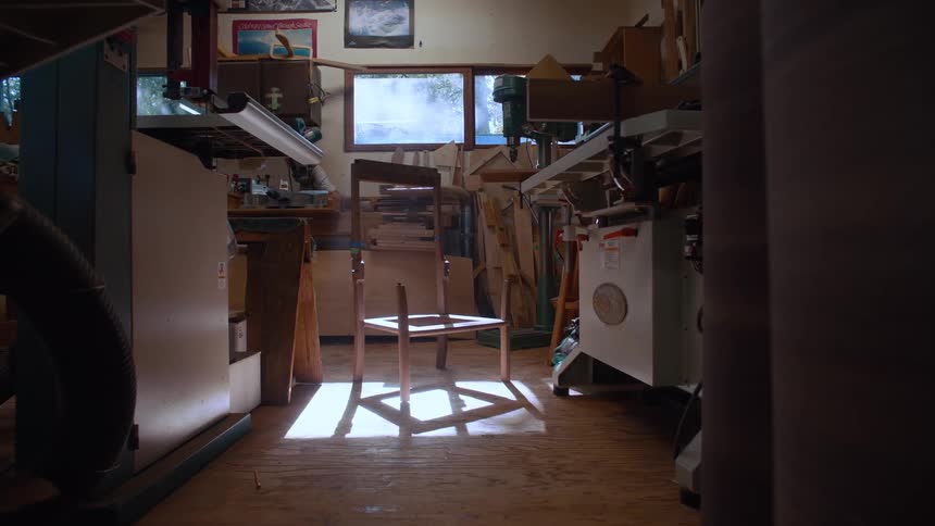 A wooden chair sits in the middle of a cluttered room
