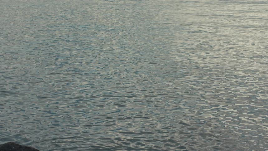Water that reflects the sun flows gently in the distance as a hillside edge appears in the foreground