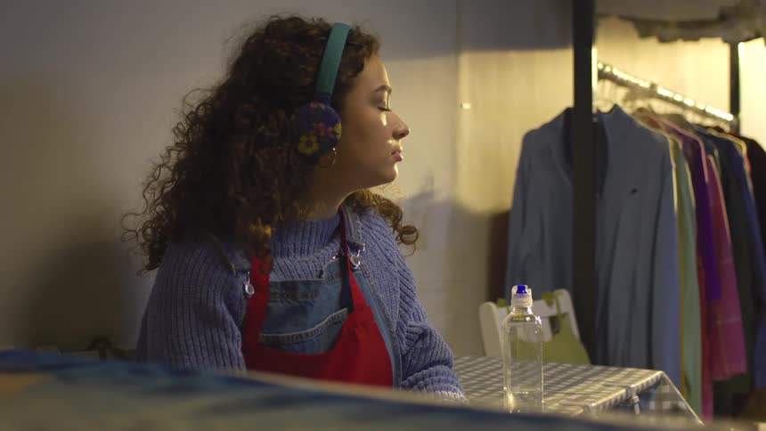 A footage of a lady listening to music and shaking her head