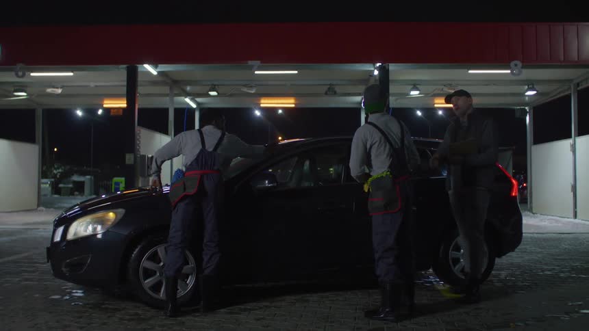 Man greeting workers who are finishing cleaning the car