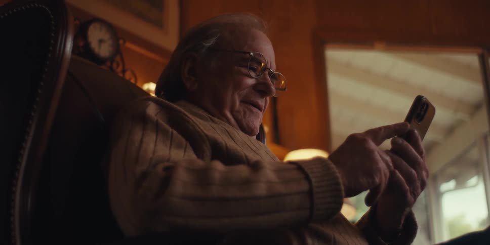 A clip of an elderly man operating a smartphone indoor