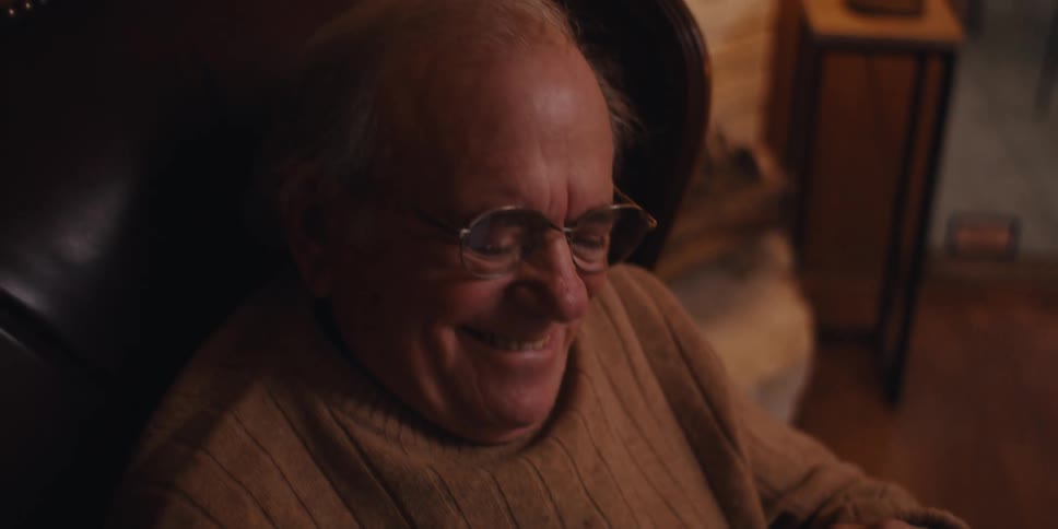 Elderly man sitting laughing while interacting with a smartphone