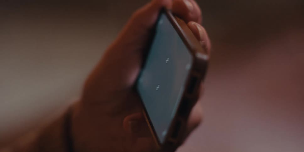 Elderly man sitting holding a smartphone sideways