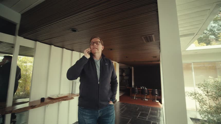 A man talks on a smartphone while walking inside a luxurious modern house